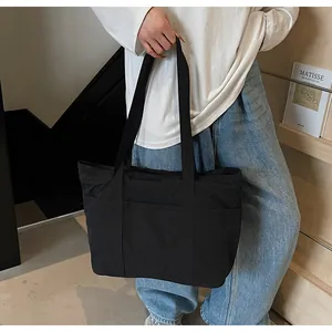 Close-up of a black minimalist large capacity tote bag with functional outer pocket