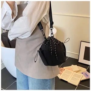 Detail der schwarzen Nylon-Beuteltasche mit dekorativem Kordelzug und Textilgurt