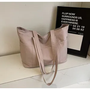 Detail of dusty pink nylon tote bag with three outer pockets on a marble surface