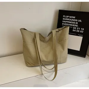 Close-up of khaki tote bag with front pocket detail on white marble surface