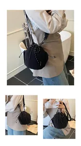 Details einer schwarzen Eimer-Tasche mit Kordelzug, Gurt und seitlichem Etikett