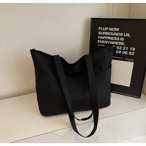 Detail of minimalist black large capacity canvas tote bag showing side pocket and wide strap