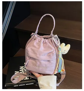 Detail view of purple nylon drawstring bucket bag with embroidered text and star charm