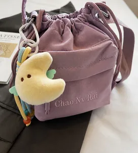 Nahaufnahme der lila Nylon-Beuteltasche mit süßem gelben Mond-Plüsch-Anhänger-Accessoire