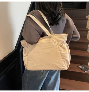 Gedetailleerd achteraanzicht van een beige gewatteerde shopper met ruches en klinknagels
