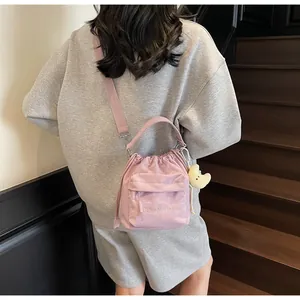 Detail of pink nylon drawstring crossbody bag featuring embroidery and yellow moon charm