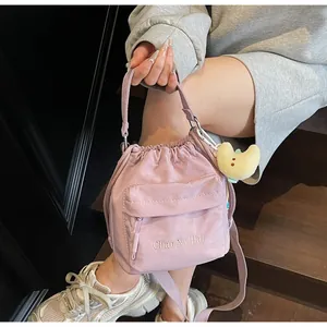 Pale purple drawstring nylon bucket bag with cute moon plush charm on wooden steps