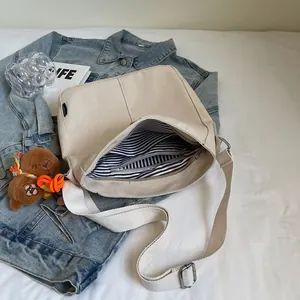 Borsa a secchiello in tela beige con tracolla larga e ciondolo a orsetto lifestyle