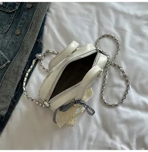 Détail du mini sac blanc avec nœud en dentelle et chaîne argentée sur tissu denim