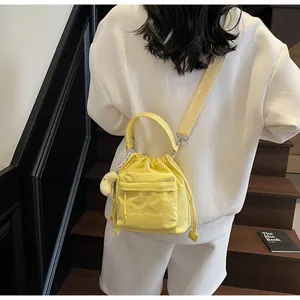Close-up of bright yellow nylon drawstring bag with small white duck plush keychain accessory