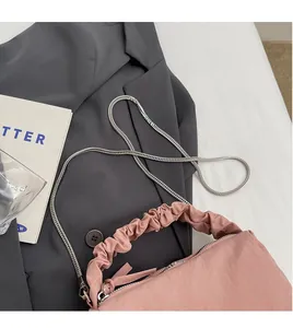Détail du sac à main plissé rose avec bandoulière chaîne argentée et fermeture éclair