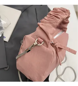 Détail du sac à main plissé rose montrant les finitions argentées et la bandoulière amovible