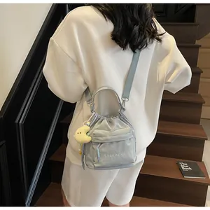 Detail of light blue nylon drawstring bucket bag with moon plush charm on stairs