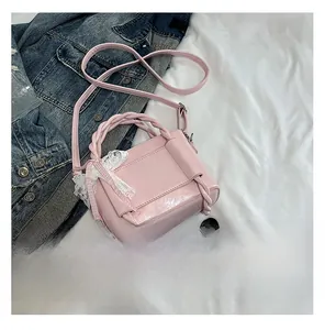 Détail du mini sac seau en cuir verni rose avec nœud en dentelle et poignée tissée