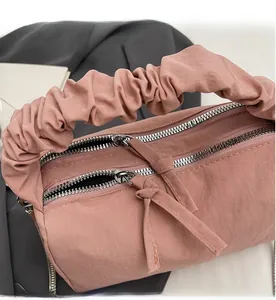 Détail du sac à main plissé rose avec double fermeture éclair et tirettes décoratives