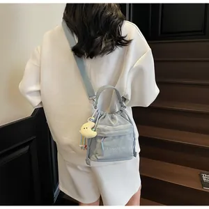 Detail of light blue nylon drawstring bucket bag with shoulder strap and plush moon charm
