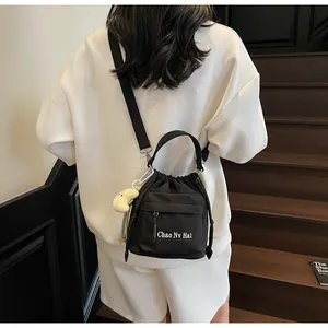 Detail of black nylon drawstring bucket bag with banana charm and crossbody strap