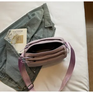 Detail view of light purple nylon crossbody bag showing three main zipper compartments