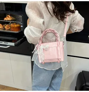 Détail du sac seau en similicuir rose avec poignée tressée et décor de nœud dentelle