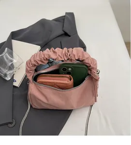 Détail du sac à main plissé rose montrant l'espace pour téléphone et portefeuille avec chaîne