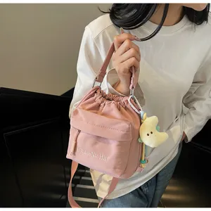 Detail of pink nylon crossbody bag with drawstring closure and yellow moon charm accessory