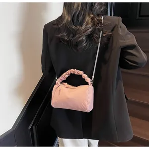 Vue arrière d'un sac à main plissé rose avec bandoulière chaîne sur blazer noir
