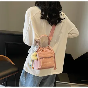 Detail of pink nylon bucket bag with drawstring closure and a plush moon keychain