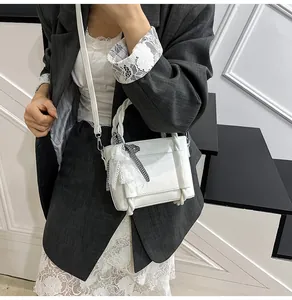 Gros plan d'un sac à bandoulière blanc orné de dentelle et d'un nœud à carreaux