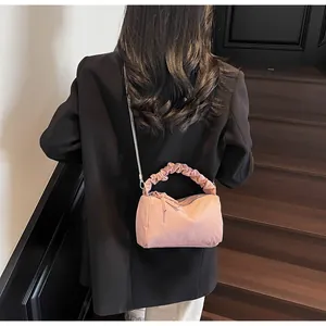 Sac polochon rose avec poignée froncée et chaîne en métal élégante dans un décor intérieur