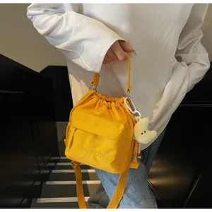 Close-up of bright yellow nylon drawstring bag featuring front pocket and moon charm