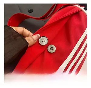 Detailed close-up of the silver magnetic buckle on a red canvas sports bag