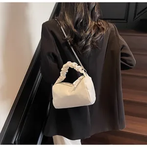 Détail d'un sac oreiller plissé blanc crème avec fine chaîne argentée et poignée froncée