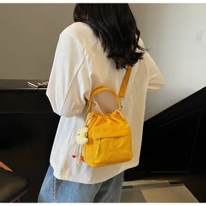 Detail of yellow nylon drawstring bucket bag with plush moon charm and shoulder strap