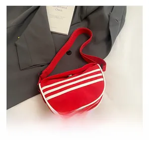 Detailed shot of red canvas crescent bag featuring white triple stripes and magnetic closure