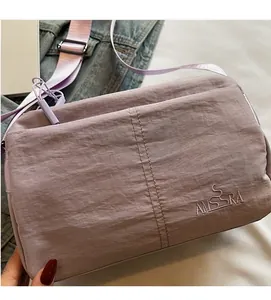 Detail of lavender nylon crossbody bag with AMSSRA embroidery and metal buckle strap