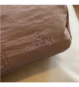 Detail of AMISSRA mauve nylon shoulder bag showing textured fabric and fine embroidery