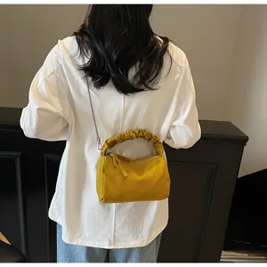 Détail d'un sac à main jaune plissé avec tissu texturé et bandoulière en chaîne