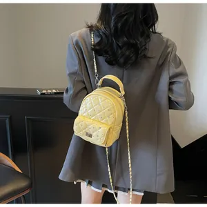 Detail of yellow quilted mini backpack with rhinestone studs and silver chain strap
