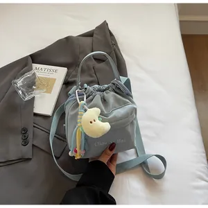 Detail of light blue nylon drawstring bucket bag with yellow moon plush charm