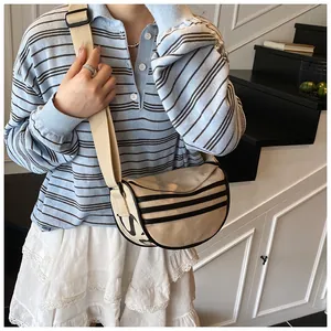 Detail of beige crescent canvas bag with black stripes and adjustable wide shoulder strap