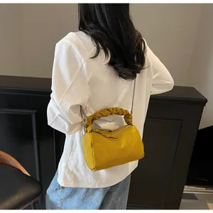 Détail d'un sac à main plissé jaune gingembre avec texture mate et chaîne argentée