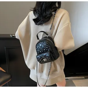 Detail view of mini black quilted backpack with silver studs and chain straps