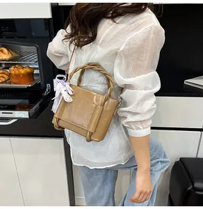 Détail du sac seau en similicuir kaki avec poignée tressée et foulard en soie violet