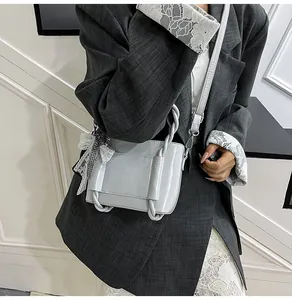 Détail du sac seau gris avec poignée torsadée et pendentif décoratif en forme de nœud