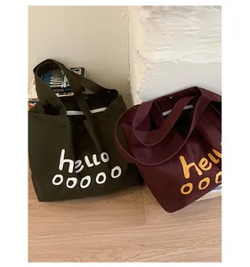 Detail of dark green and burgundy canvas tote bags featuring stylish letter prints