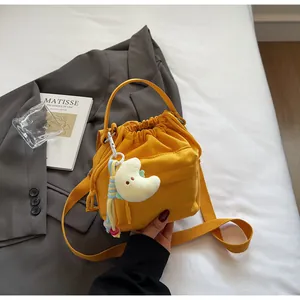 Detail of yellow nylon drawstring bucket bag with plush moon charm and crossbody strap