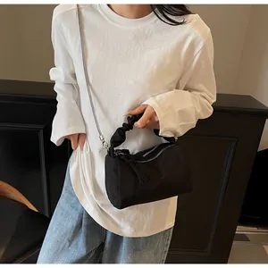 Détail d'un sac à main plissé noir avec double fermeture éclair et chaîne argentée