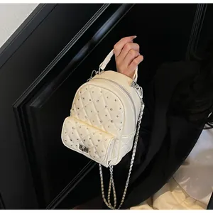 Close-up of quilted cream mini backpack with rhinestone studs and metal chain strap