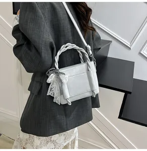 Détail du sac seau bleu clair en similicuir avec poignée tissée et ruban en dentelle