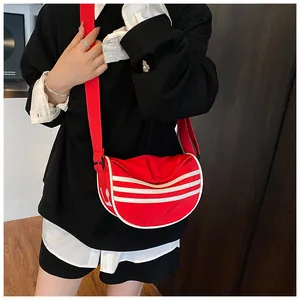 Detail view of red crescent canvas bag with white triple stripes and adjustable strap